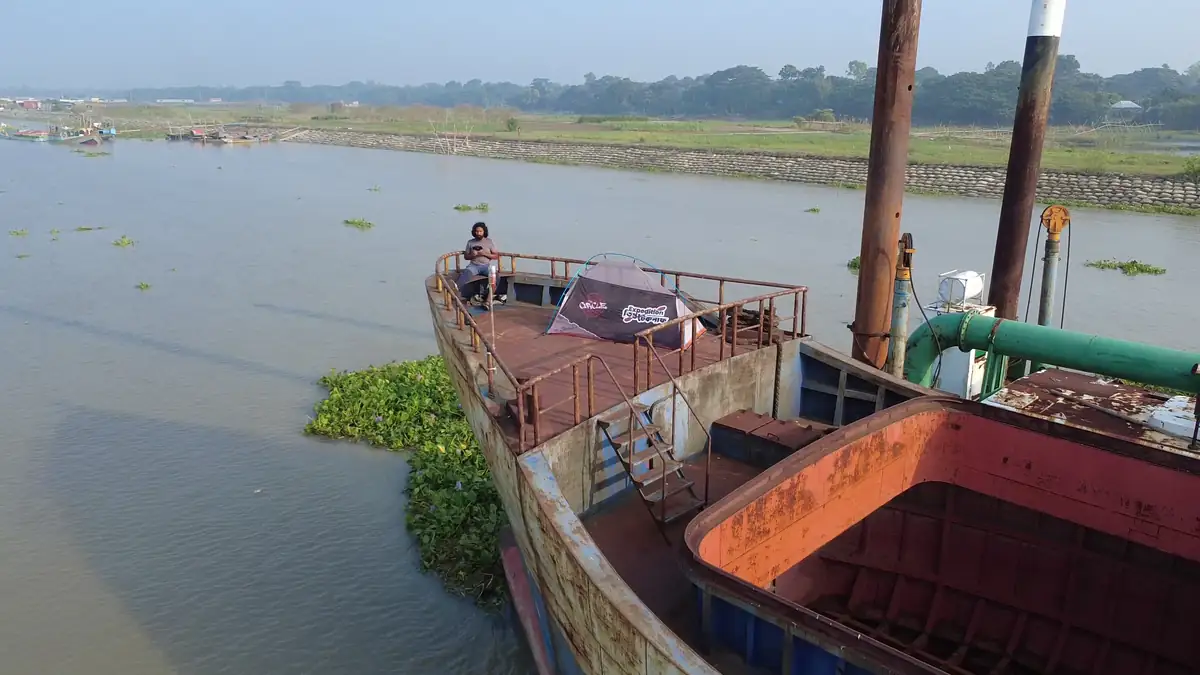 নদীর ধারে বড় নৌযানের খোলা ডেকে অভিযানের ছোট তাঁবু