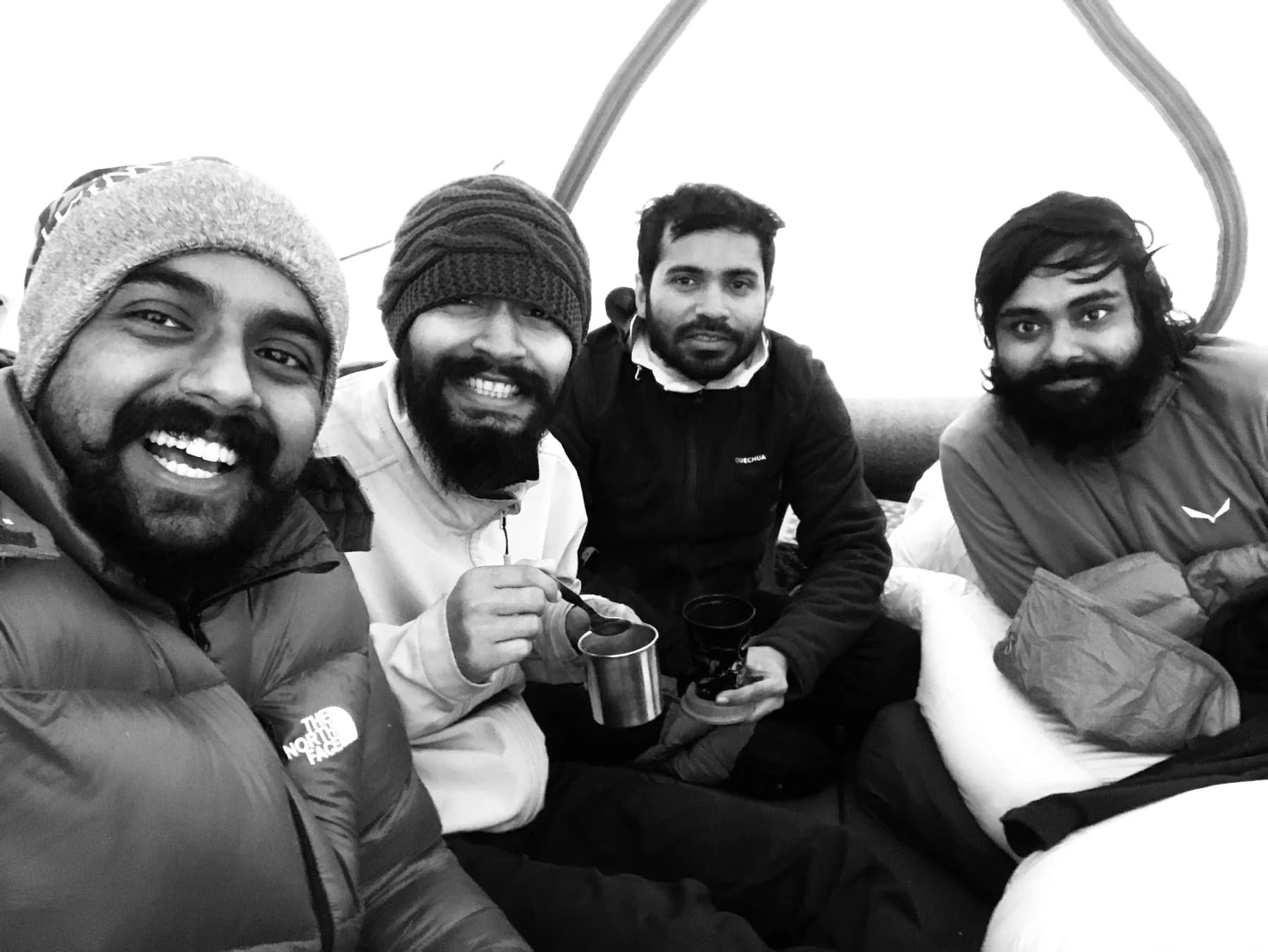 Four expedition teammates together indoors, two holding metal cups